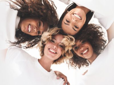 Image of a pretty positive cheery young women multiracial friends posing isolated over white wall background looking at camera.